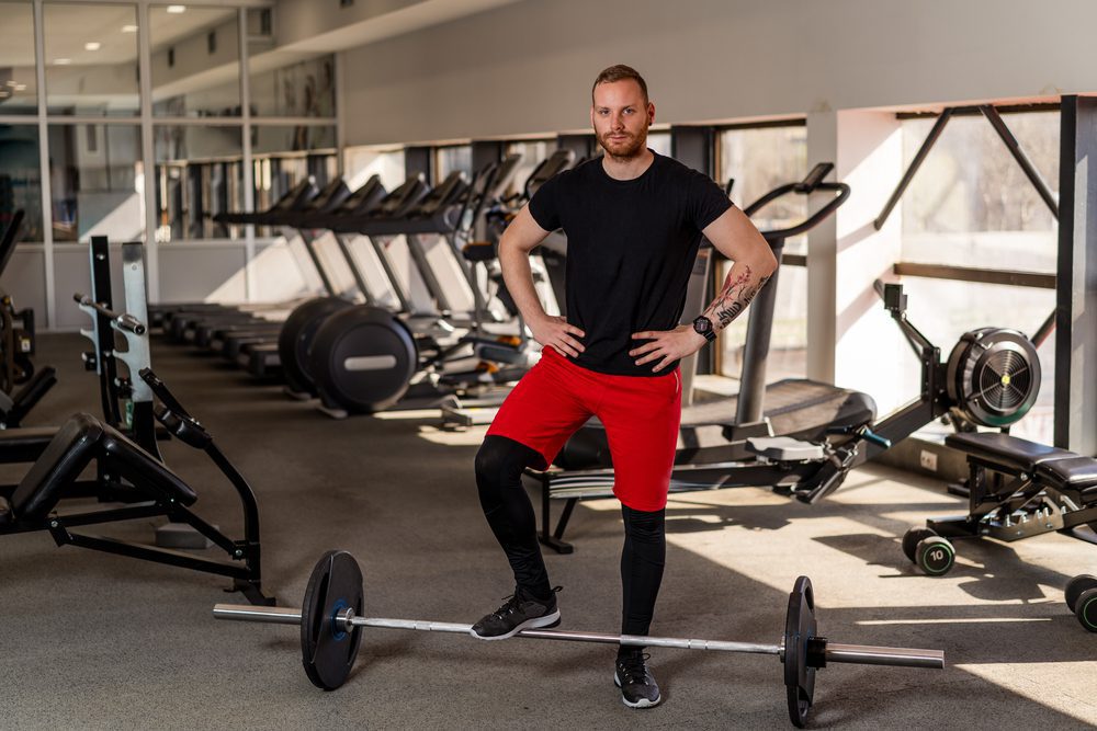 Man standing over a weight in a gym