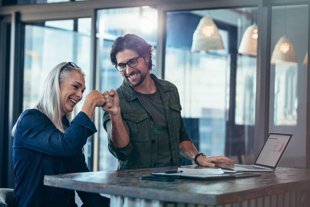 business partner coaching | man and woman fist bumping at work