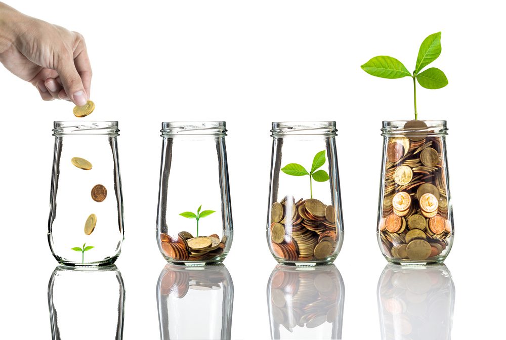 financial planning business coach | hand putting coins into jars