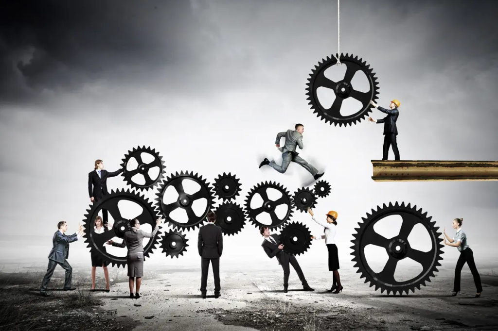 Best leadership books | Team of businesspeople standing on top of cogs, piecing together the team. 