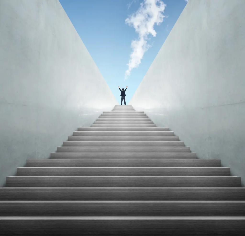 business coach uk | Person standing triumphantly at the top of marble stairs.
