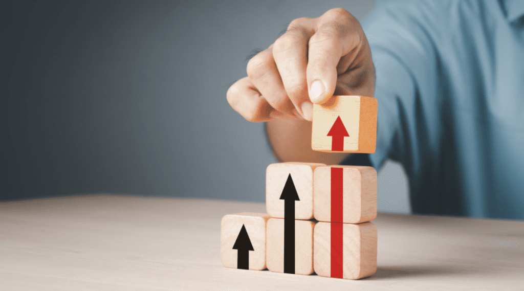 Growth agency | Wooden blocks with upwards arrows stacked on top of each other.