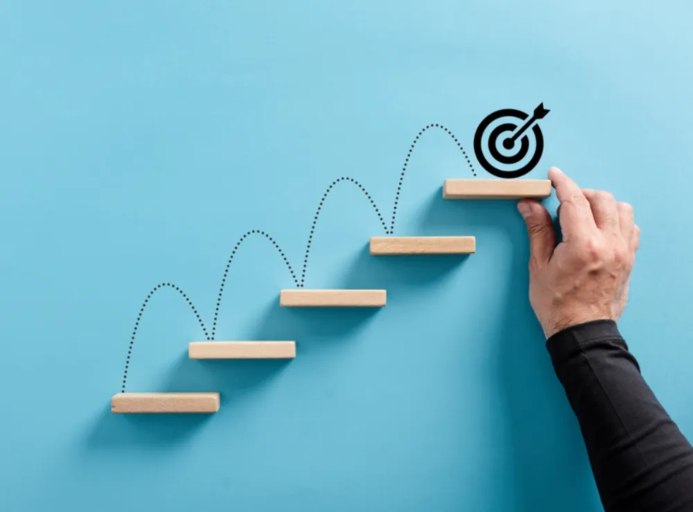 Business coach | Person drawing a target jumping up stairs.